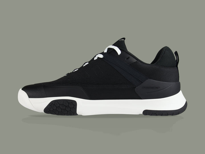 Side view of black and white PB5star Court2 performance sneaker featuring breathable mesh upper, durable sole with hexagonal grip pattern, and modern design.