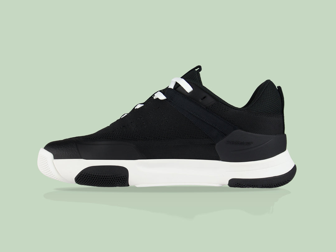 Side view of black and white PB5star Court2 performance sneaker featuring breathable mesh upper, durable sole with hexagonal grip pattern, and modern design.