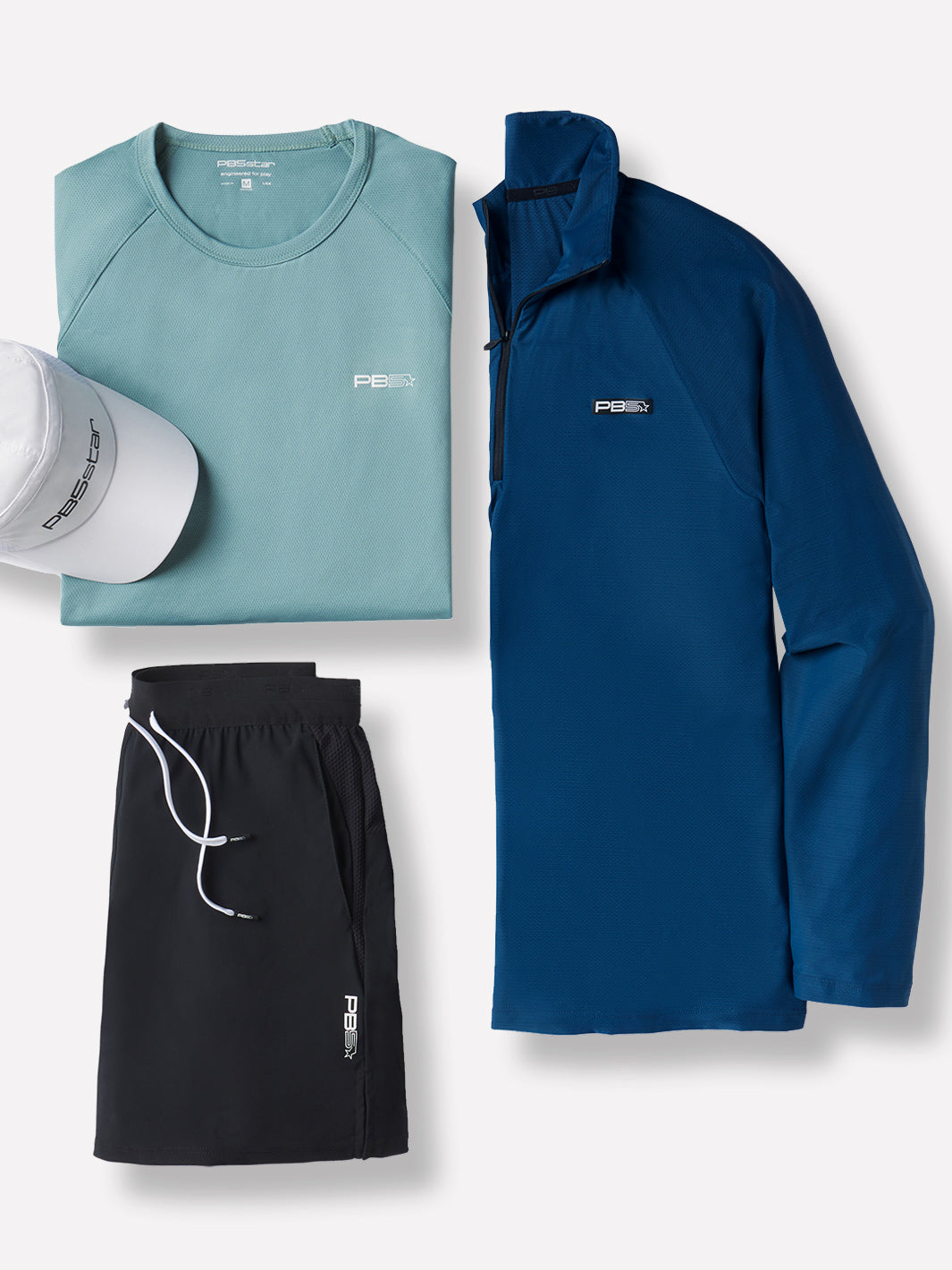 Flat lay of athletic apparel featuring an Arctic Core Performance Tee, white PB5star Signature cap, black Signature Court Shorts, and astral blue M's Long Sleeve Layering Tee.