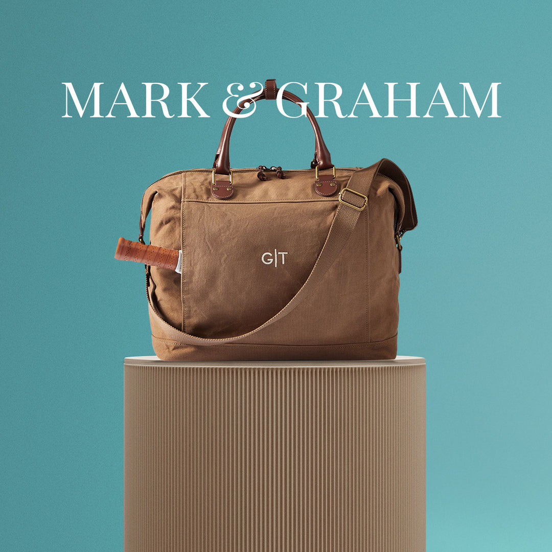 Mark & Graham personalized brown canvas duffel bag with leather handles, displayed on a beige stand against a teal background, featured as part of The Ultimate Gear Giveaway with PB5star, ideal for travel and gifting.