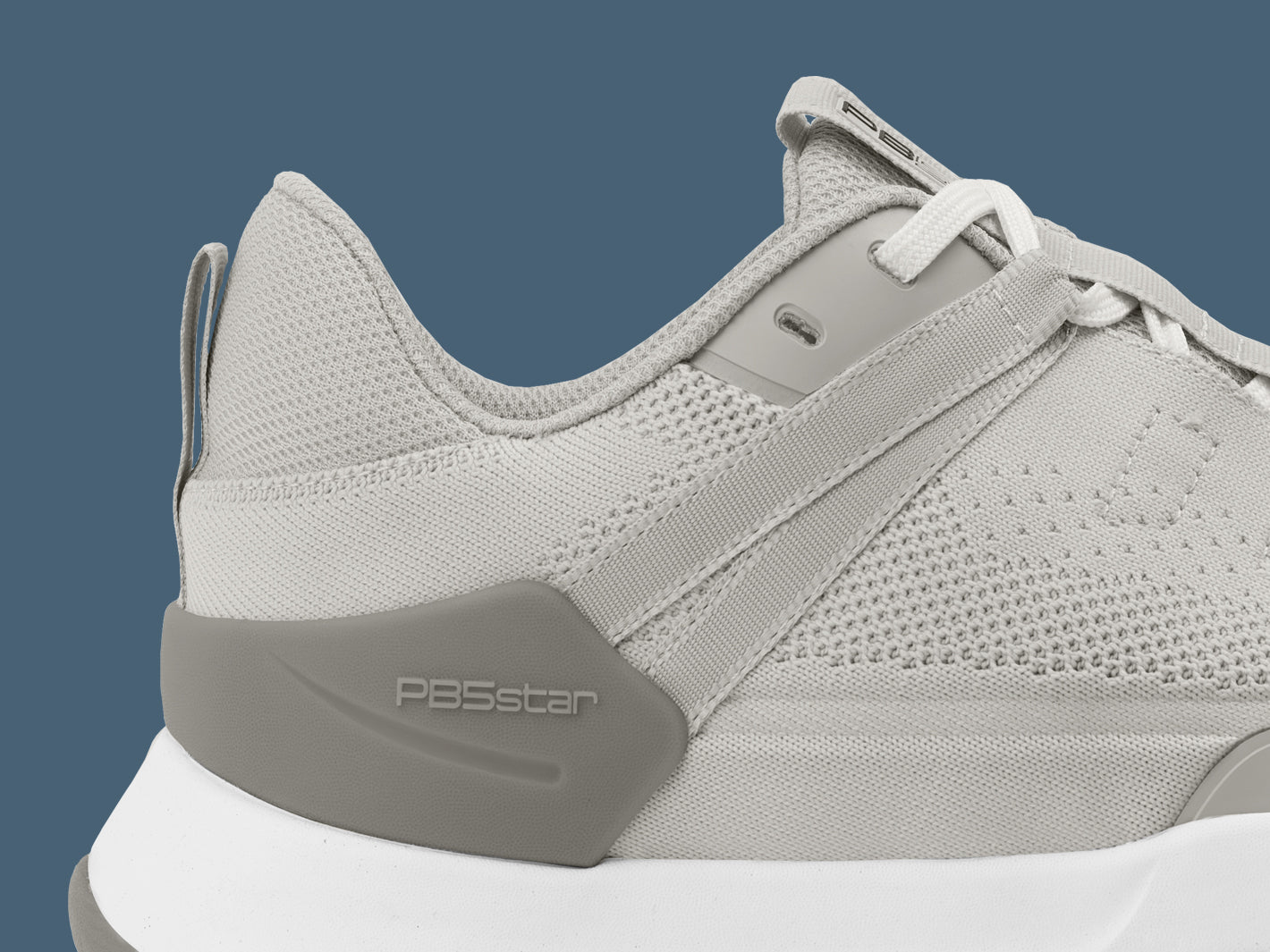 Close-up of PB5 Court2 athletic shoe in light grey with PB5star branding, highlighting the breathable knit upper and supportive heel design.