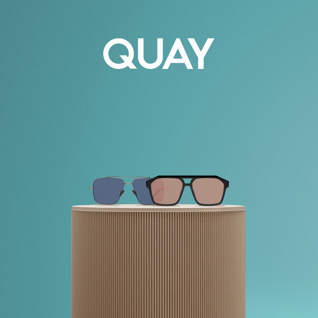 Stylish Quay sunglasses displayed on a textured beige stand against a vibrant teal background, win the Ultimate Gear Giveaway with PB5star and Quay.