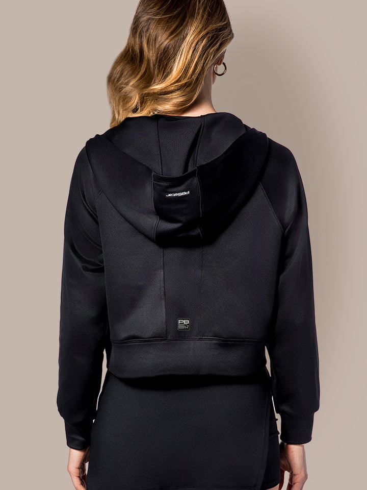 Rear view of a woman wearing PB5Star's black Cropped Performance Hoodie, showcasing the comfortable fit and hood detail.