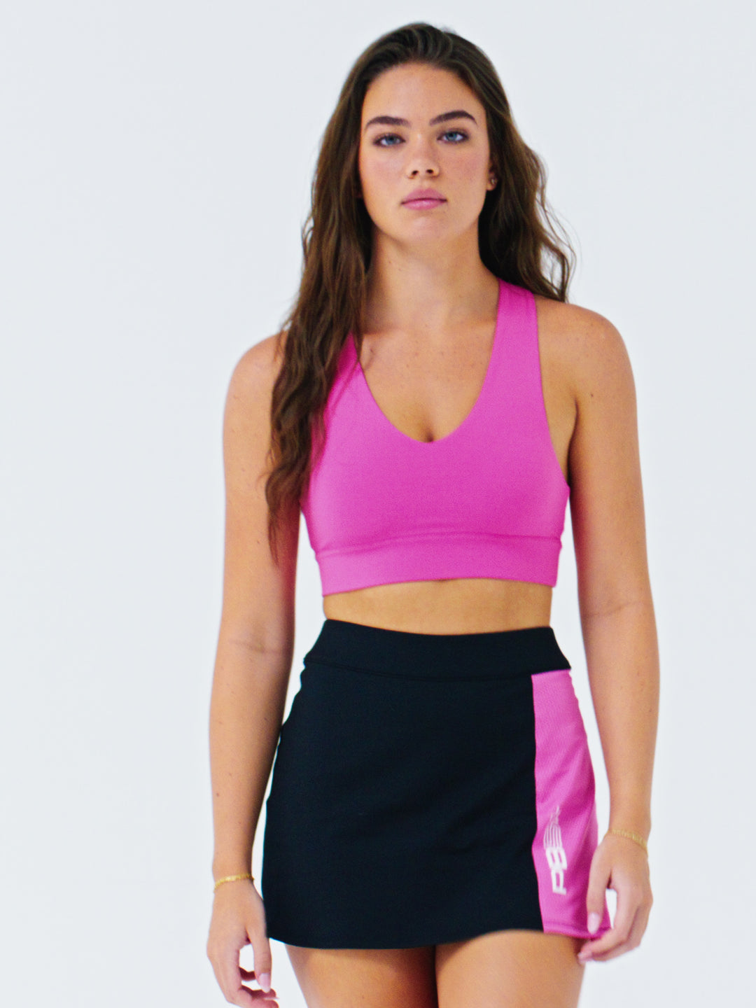 Model wearing PB5star X-over sports bra in Pink and Mesh Panel Pickleball Skirt in black-pink, showcasing the activewear in a video.