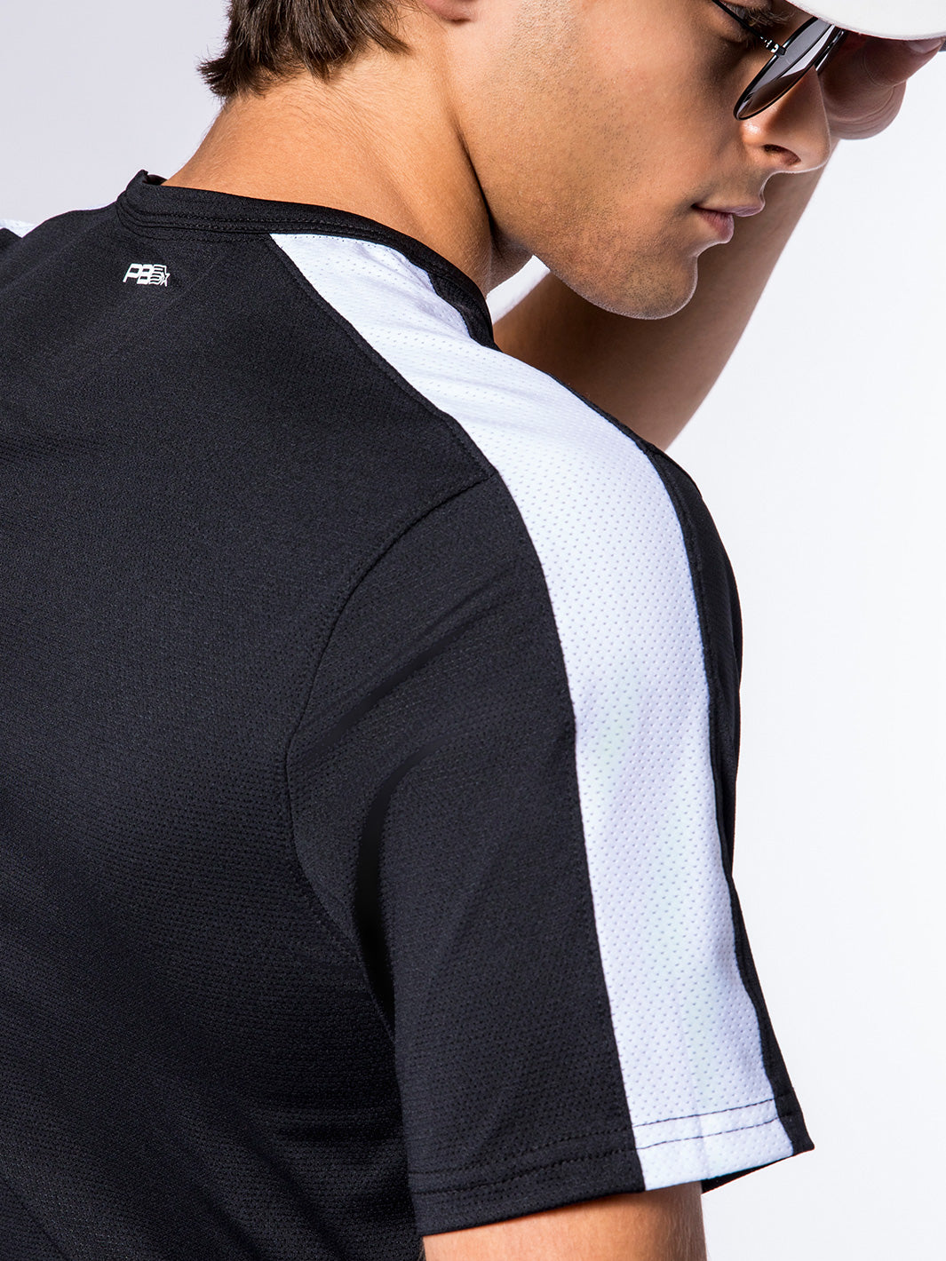 Close-up side view of a man wearing PB5Star's Core Vented Tee, featuring white mesh ventilation panels on black fabric.