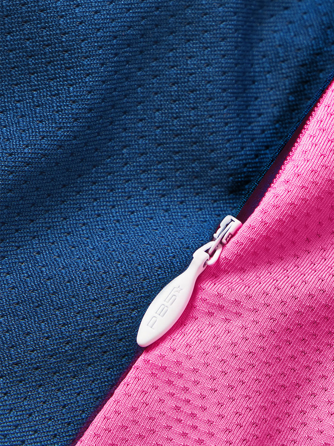 Close-up of PB5star logo on zipper pull against astral blue and pink fabric of the Women's Vented Court Tee